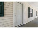 Exterior view of a white condo door with dark green shutters on windows and gray tile flooring at 545 White River Dr. # 15 D, Myrtle Beach, SC 29579
