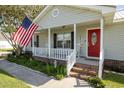 Inviting front porch with red door, American flag, rocking chairs, and well-maintained landscaping at 706 Chippendale Dr., Myrtle Beach, SC 29588