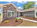 Home's exterior with stone accents and fresh landscaping featuring lush plants, and a sidewalk leading to the front door at 718 Highway 348, Loris, SC 29569