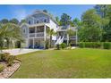 Beautiful two-story coastal home featuring a spacious lawn, lush landscaping, and classic architecture at 77 Streater Ln., Pawleys Island, SC 29585