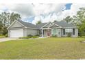 Well-maintained one-story home with light gray siding, a red front door, and a spacious front yard at 908 Hornbeam Ct., Loris, SC 29569