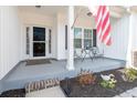 Cozy front porch with seating, an American flag, and decorative landscaping at 250 Ole Maple St., Loris, SC 29569