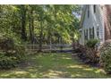 Green backyard featuring a white picket fence, mature trees, and ample space for outdoor activities or relaxation at 3772 Brown Bark Ln., Murrells Inlet, SC 29576