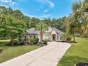 Stately single-Gathering home featuring mature landscaping and a long driveway surrounded by grass at 5916 Falcon Landing Circle, North Myrtle Beach, SC 29582