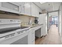 Galley kitchen with white appliances and cabinets leads to living area with ocean view at 6900 Ocean Blvd. # 935, Myrtle Beach, SC 29572