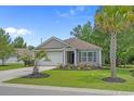 Single-story home boasting a well-maintained lawn with flowering beds and palm trees at 100 Oak Leaf Dr., Longs, SC 29568