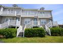 Close up of the exterior townhouse complex with white stairs and greenery at 112 3Rd Ave. S # B, Surfside Beach, SC 29575