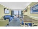 Cozy living room with a comfortable blue sofa, a dining table, and balcony access with ocean views at 3000 N Ocean Blvd. # 220, Myrtle Beach, SC 29577