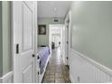 Inviting hallway with neutral tones, tiled flooring, and white wainscoting leads to a bedroom and living area at 5905 South Kings Hwy. # 135, Myrtle Beach, SC 29575