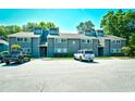 Exterior of building showing units with gray siding, a parking area, green space, and mature trees at 10301 N Kings Hwy. # 21-5, Myrtle Beach, SC 29572