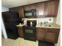 Functional kitchen featuring black appliances, granite countertops, and dark wood cabinets at 200 76Th Ave. N # 608, Myrtle Beach, SC 29572