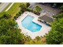 Aerial view of the sparkling community pool with ample seating and a clubhouse surrounded by mature trees at 306 River Rock Ln. # 1306, Murrells Inlet, SC 29576