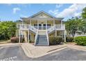 Yellow two-story condo building with shared stairs and landscaping at 5038 Belleglen Ct. # 202, Myrtle Beach, SC 29579