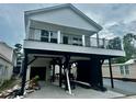 Two-story home with white siding, black trim, elevated design and a covered parking area beneath the house at 6001 - 1766 S Kings Hwy., Myrtle Beach, SC 29575