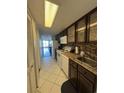 Galley kitchen featuring dark wood cabinets, white appliances, and tiled floors at 7509 N Ocean Blvd. # 1205, Myrtle Beach, SC 29572