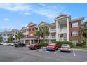 Well-maintained condos with attractive architecture, brick facade, white railings, and tropical landscaping at 1000 Ray Costin Way # 107, Garden City Beach, SC 29576