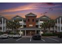 Beautiful condo building showcasing manicured landscaping, palm trees, and covered balconies at 1000 Ray Costin Way # 107, Garden City Beach, SC 29576