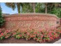 Signage for Tupelo Bay Golf Villas with brick surround, lovely landscaping, and mature trees in the background at 1000 Ray Costin Way # 107, Garden City Beach, SC 29576