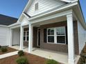 Charming brick home with covered porch, supported by white columns, and neat landscaping at 1033 Jase Dr., Longs, SC 29568