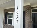 Close up of house number, 1033, on a brick home's porch column, complemented by black shutters at 1033 Jase Dr., Longs, SC 29568