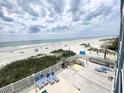 Panoramic view of a beach, blue water, and cloudy sky, with deck and lounge chairs in foreground at 116 S Waccamaw Dr. # 205, Murrells Inlet, SC 29576