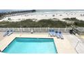 Elevated shot of a clear swimming pool with lounge chairs, a beach, and pier at 116 S Waccamaw Dr. # 205, Murrells Inlet, SC 29576