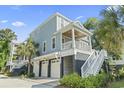 Charming elevated coastal home featuring a covered porch, white railings, and convenient ground-level garage at 18 Coastal Breeze Trail, Pawleys Island, SC 29585