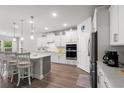 Modern kitchen with white cabinetry, stainless steel appliances, an island with bar seating, and wood floors at 57 Eagle Claw Dr., Carolina Shores, NC 28467