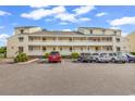 Condo building showing parking area with multiple cars and well-maintained landscaping at 1100 Possum Trot Rd. # D-205, North Myrtle Beach, SC 29582