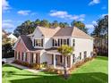 Spacious home with brick accents, a manicured lawn, landscaping, and a lovely palm tree under a bright blue sky at 1303 Bermuda Grass Dr., Myrtle Beach, SC 29579