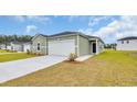 Lovely light green home featuring a white garage door, complemented by a well-maintained lawn at 1372 Palm Springs Paloma Dr, Longs, SC 29568
