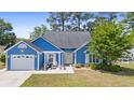 Charming blue single-Gathering home with a lush green lawn, white trim, and a lovely front-yard patio area at 284 Nature Trail, Little River, SC 29566