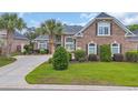 Charming brick home with manicured lawn, mature landscaping, and elegant architectural details at 372 Waterfall Circle, Little River, SC 29566