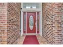 Close-up of a decorative red front door with glass panels and brick surround at 372 Waterfall Circle, Little River, SC 29566