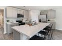 Well-lit kitchen featuring a large island with bar seating, stainless appliances, and stylish gray cabinetry at 4473 East Coast Ln., Shallotte, NC 28470