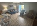 Living room with wood-look flooring, comfortable seating, and a sliding glass door to the balcony at 5001 Little River Rd. # E-306, Myrtle Beach, SC 29577