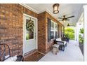 Inviting brick porch with a ceiling fan, white pillars, and comfortable seating at 672 Ashley Manor Dr., Longs, SC 29568