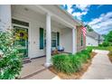 Inviting front porch with decorative wreath, seating, and an American flag, creating a welcoming entrance at 100 Woodlyn Ave., Little River, SC 29566
