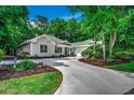 Landscaped home exterior showcasing a concrete driveway, well-manicured lawn, and lush, mature trees at 1204 Pine Valley Rd., North Myrtle Beach, SC 29582