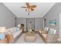 Cozy living room with neutral walls, wicker furniture set, ceiling fan, and beach-themed décor at 125 Balsa Dr., Longs, SC 29568