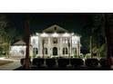Nighttime view of an elegant home showcasing classic architecture, illuminated columns, and meticulously landscaped grounds at 4110 Gray Heron Dr., North Myrtle Beach, SC 29582