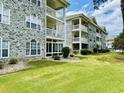 The back of the condo with white brick, balconies and screened in porches, and manicured landscaping at 4783 Wild Iris Dr. # 101, Myrtle Beach, SC 29577