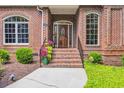 Welcoming brick front porch with beautiful door and potted colorful flowers at 520 Chapman Loop, Pawleys Island, SC 29585