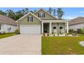 Inviting home with green siding, a white garage door, and a cozy front porch with seating at 736 Flowering Branch Ave., Little River, SC 29566