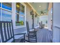 Relaxing front porch featuring rocking chairs, lighting and ceiling fans at 8185 Sandlapper Way, Myrtle Beach, SC 29572