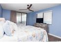 Bedroom with two beds, blue walls, ceiling fan, dresser, and a sliding glass door to balcony at 8560 Queensway Blvd. # 1109, Myrtle Beach, SC 29572