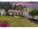 Charming single-Gathering home with lush green lawn, manicured landscaping and a driveway at dusk at 1105 Lampwick Ln., Murrells Inlet, SC 29576