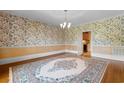 Spacious dining room with hardwood floors, decorative wallpaper, and elegant chandelier lighting at 115 Ford Ave, Mullins, SC 29574