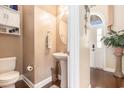 Cozy half bath with pedestal sink, hardwood floors, and decorative fixtures next to the front entrance at 1367 Bermuda Grass Dr., Myrtle Beach, SC 29579