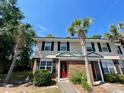 Charming townhouse with palm trees, a red front door, and well-maintained landscaping at 1432 Highway 544 # B2, Conway, SC 29526